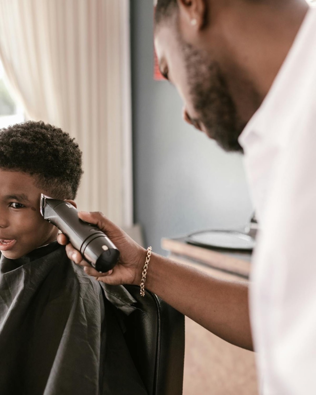 A barber giving a young client a careful clipper cut at Explicit Barbershop.