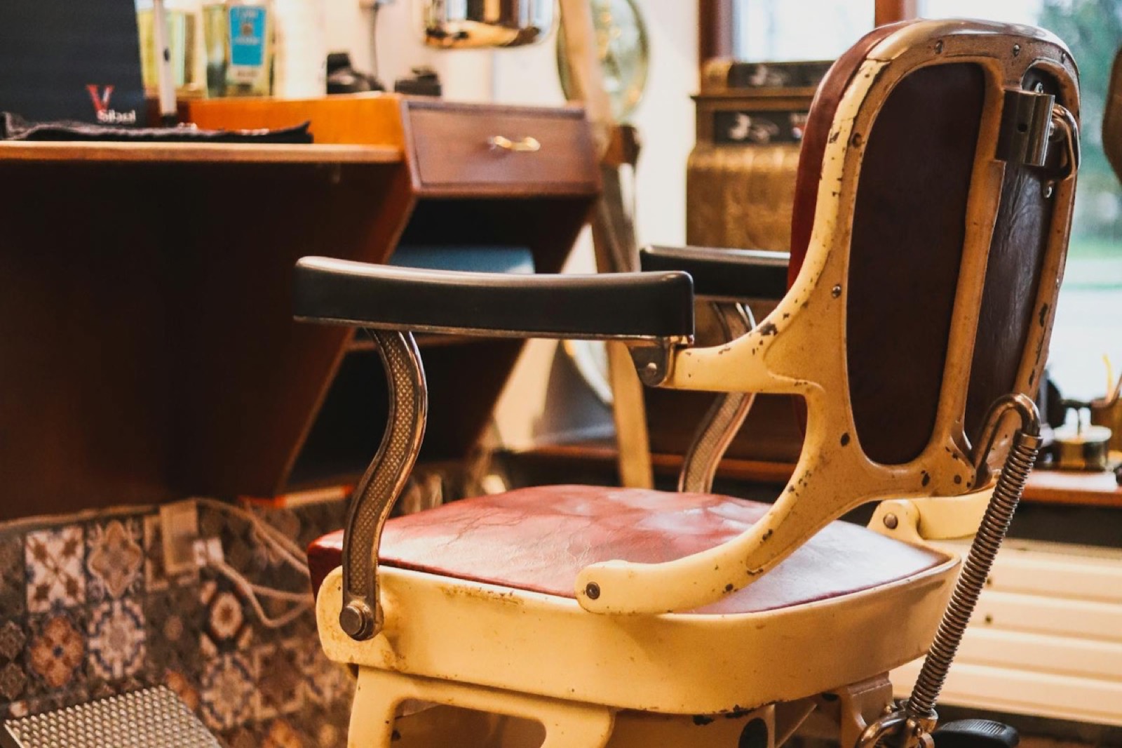 Vintage leather barber chair with worn red cushion in warm afternoon light at Explicit Barbershop.